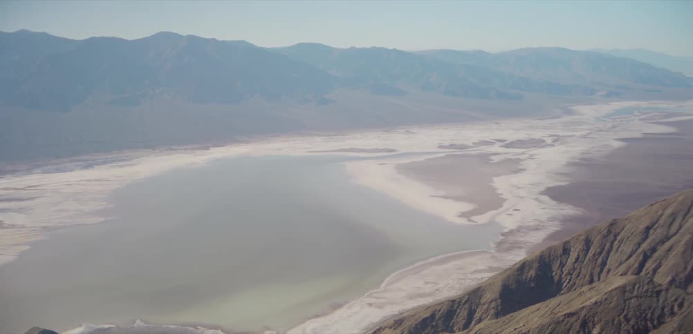 A majestic panoramic view from a high mountain reveals the vast salt flats and arid landscape of Death Valley