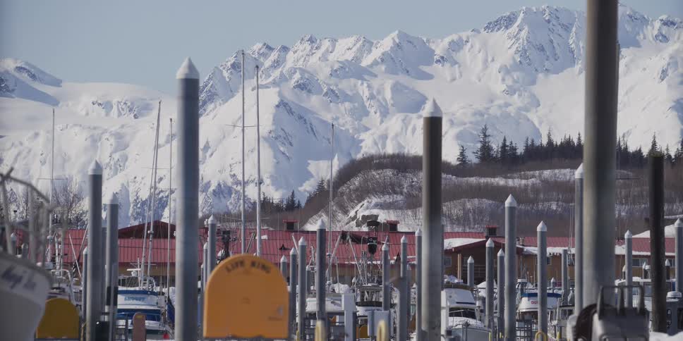 A scenic view of a snowy boat harbor with majestic white mountains rising in the background
