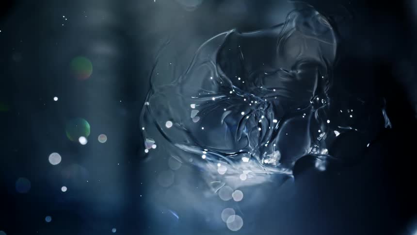 An ethereal, translucent organism floats in a dark, liquid space surrounded by sparkling particles and bokeh