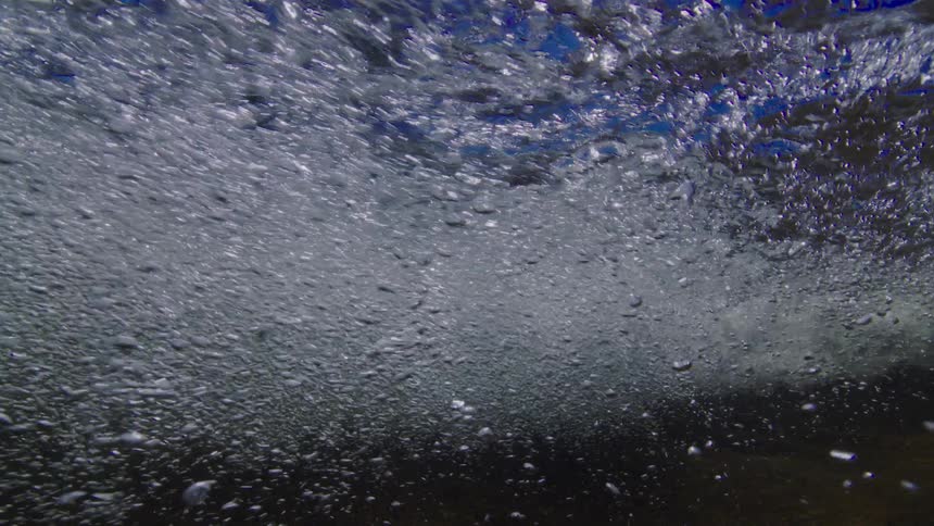 A mesmerizing underwater slow-motion view of countless air bubbles rising through turbulent water