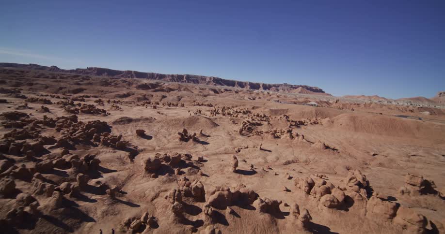 A sweeping aerial view reveals the vast and unique sandstone hoodoos of Goblin Valley, Utah, under a clear blue sky