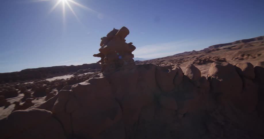 A slow, cinematic orbiting shot captures the unique hoodoo rock formations of Goblin Valley on a bright, sunny day