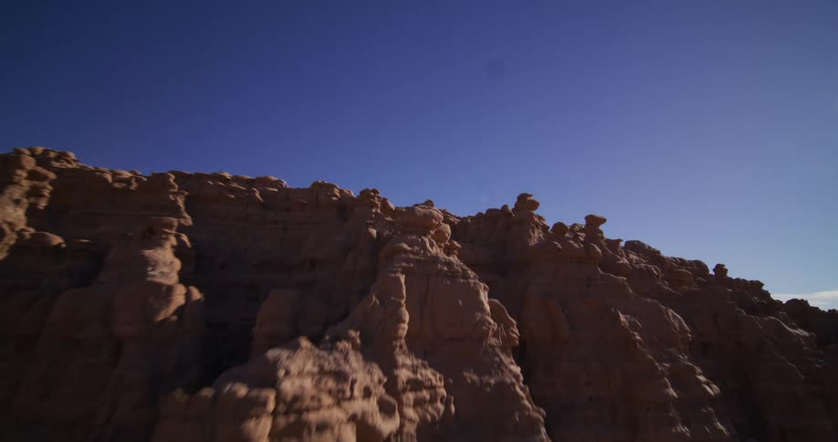 A sweeping aerial shot flies over the unique hoodoo rock formations of Goblin Valley State Park, revealing the vast desert landscape