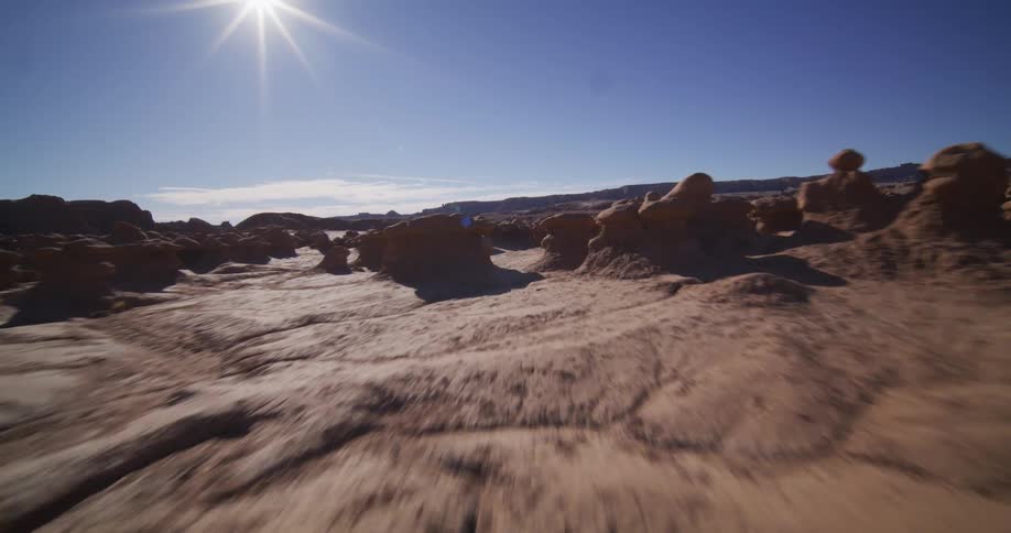 A low-angle point-of-view shot speeds through the otherworldly desert landscape of Goblin Valley, Utah