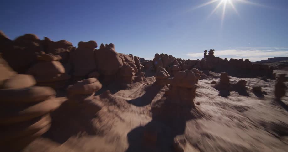 A thrilling aerial journey swooping low over the otherworldly hoodoo rock formations of a sun-drenched desert valley