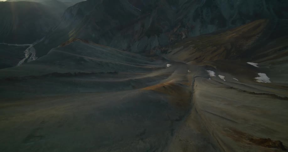 An epic aerial journey along a colorful mountain spine, revealing a sweeping valley below at sunset