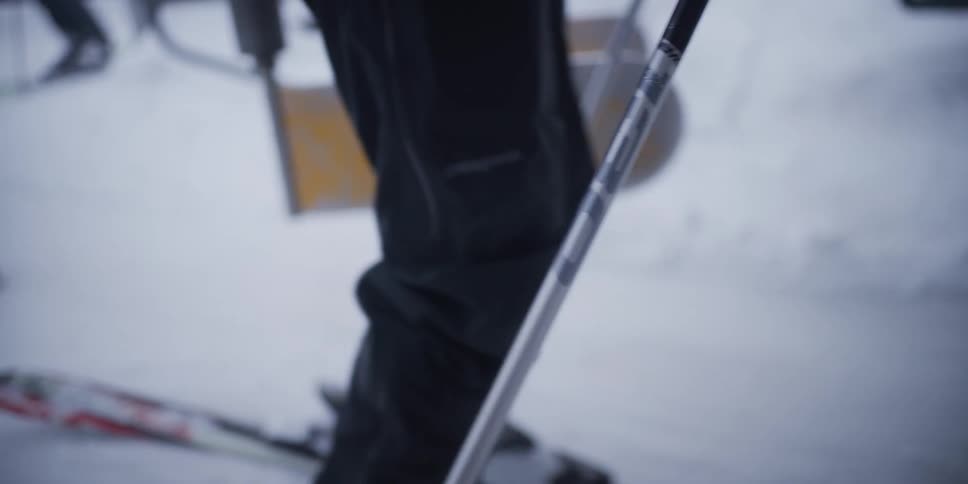 A slow-motion, artistic close-up of a skier's boots and equipment resting in the snow