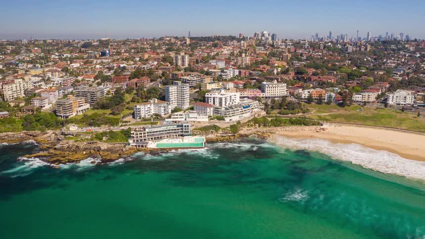 Aerial hyperlapse of Sydney's iconic Bondi Beach and Icebergs Pool on a clear sunny day