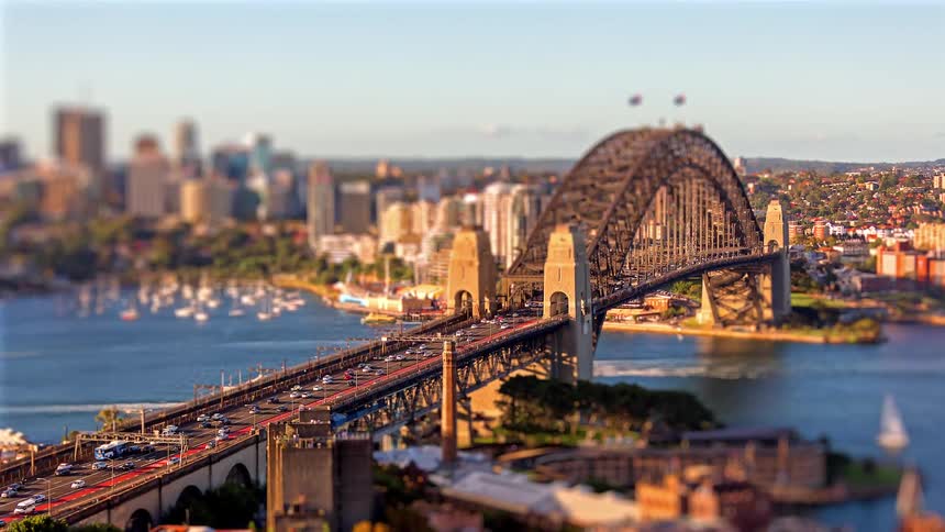 A stunning tilt-shift time-lapse captures busy traffic crossing the Sydney Harbour Bridge with the city skyline in the background