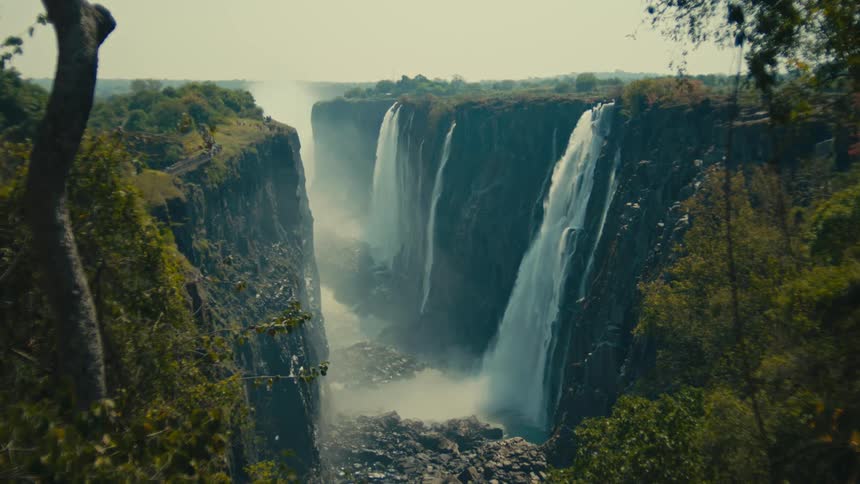 A stunning, wide view of Victoria Falls as it thunders down a massive gorge, with mist rising from below