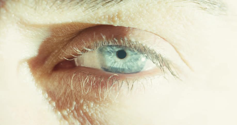 An extreme close-up of a blue eye with a single tear slowly running down the cheek