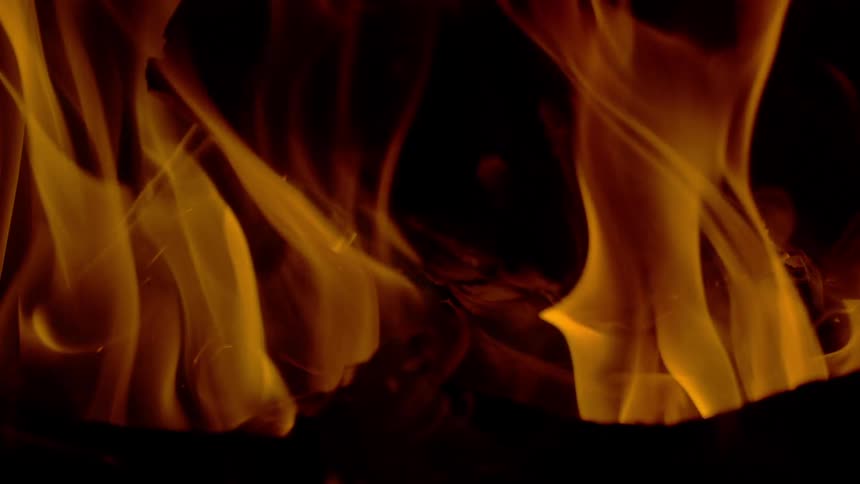 A close-up slow-motion shot of mesmerizing orange flames dancing against a dark background