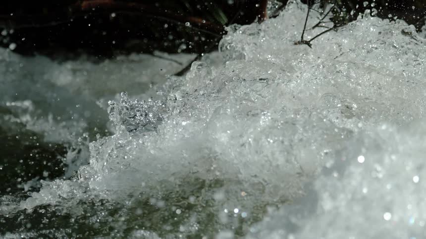 An ultra slow motion close up of a powerful current splashing and spraying