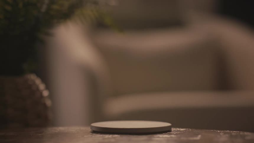 Close-up of a hand picking up a steaming hot mug and placing it back down on a coaster in a cozy, dimly lit room