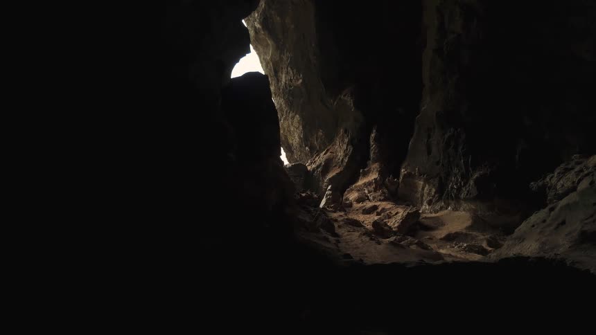 A slow and mysterious journey through a dark, rocky cave reveals a bright exit ahead