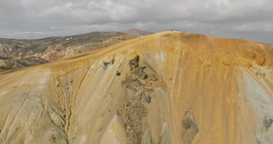 A slow aerial push-in shot of the vibrant, colorful mountain ridges of Landmannalaugar in the Icelandic highlands