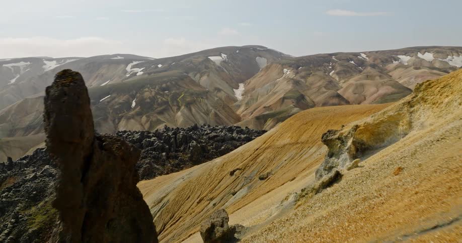 A slow aerial push-in reveals the dramatic and colorful volcanic landscape of the Icelandic highlands