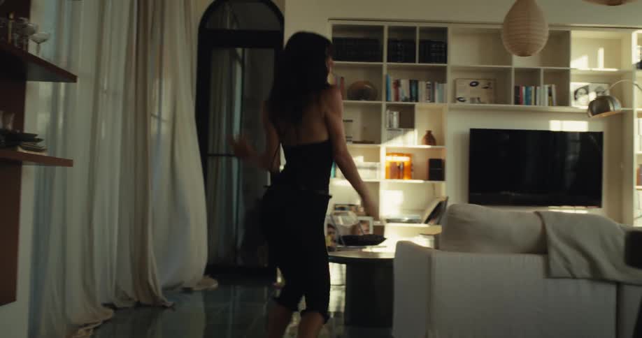 A carefree woman expresses her joy by dancing energetically in her beautiful, sunlit living room