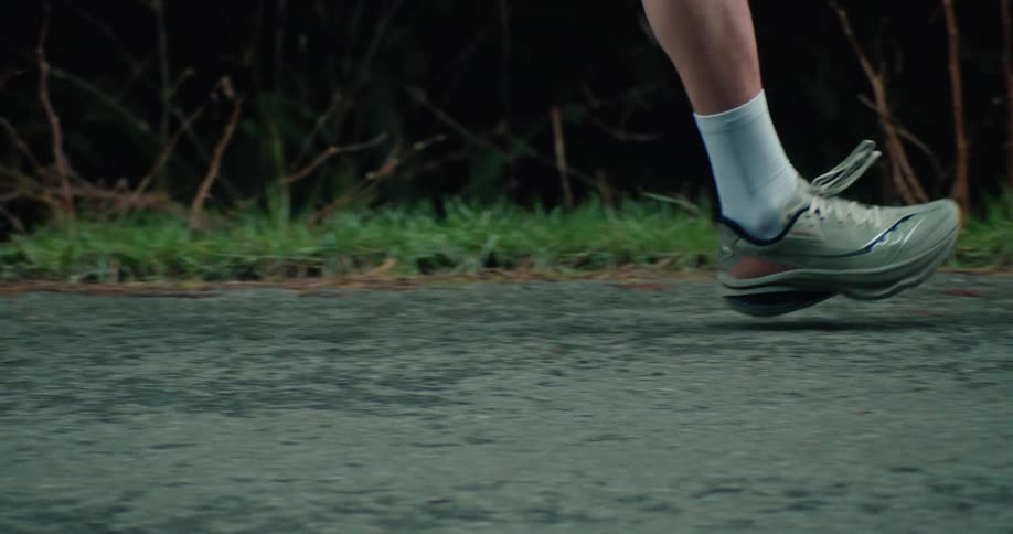 A slow-motion close-up of a runner's athletic shoes pounding the pavement during a morning jog