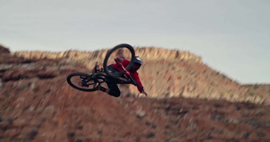 An extreme mountain biker performs an impressive mid-air trick against a rugged red rock backdrop