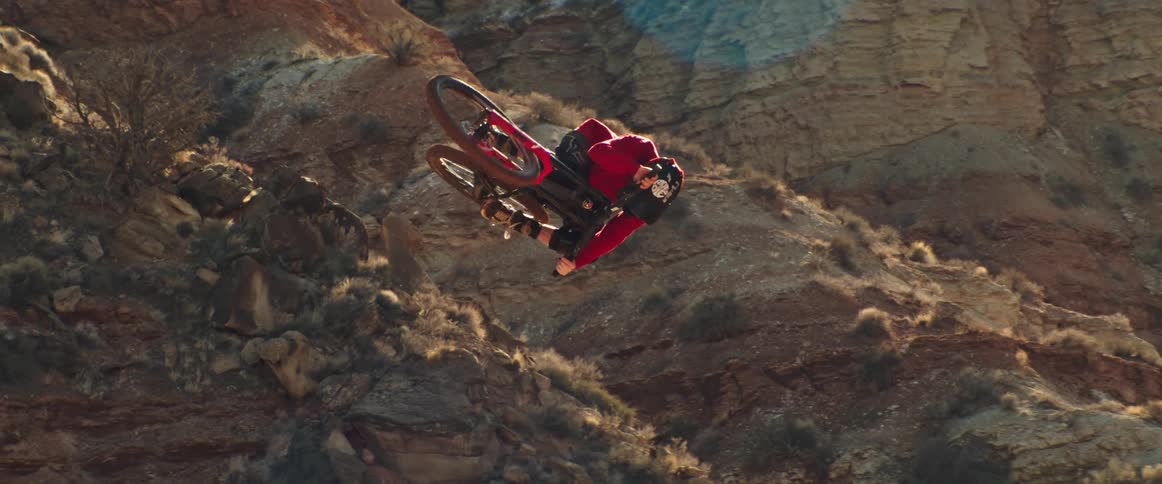 A mountain biker performs a spectacular style trick in super slow motion with a desert background during golden hour
