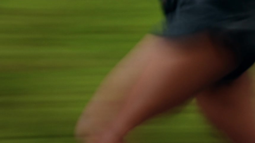 A motion blur shot follows a woman running quickly through a green forest