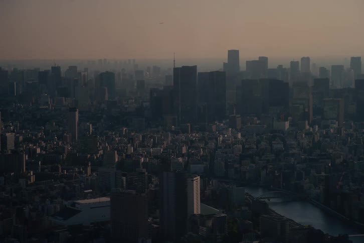 A vast and hazy urban landscape with skyscrapers silhouetted against a dim, muted sky