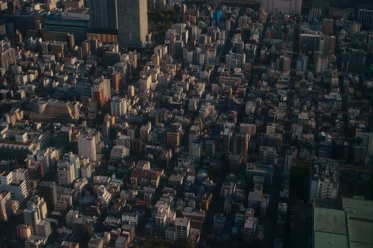 A high-angle static shot captures the vast and dense urban landscape of Tokyo during a beautiful sunset