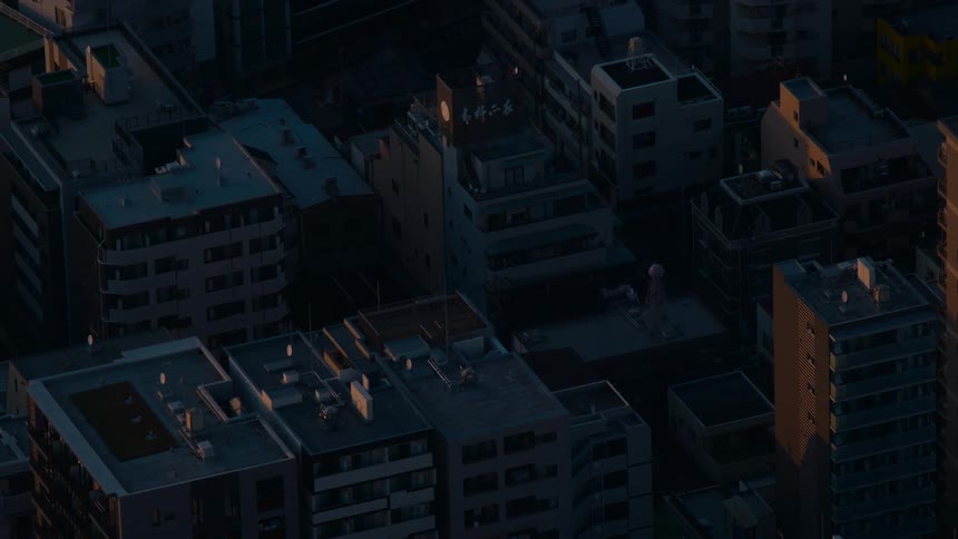 High-angle timelapse of golden hour sunlight and shadows moving across the rooftops of a dense urban cityscape