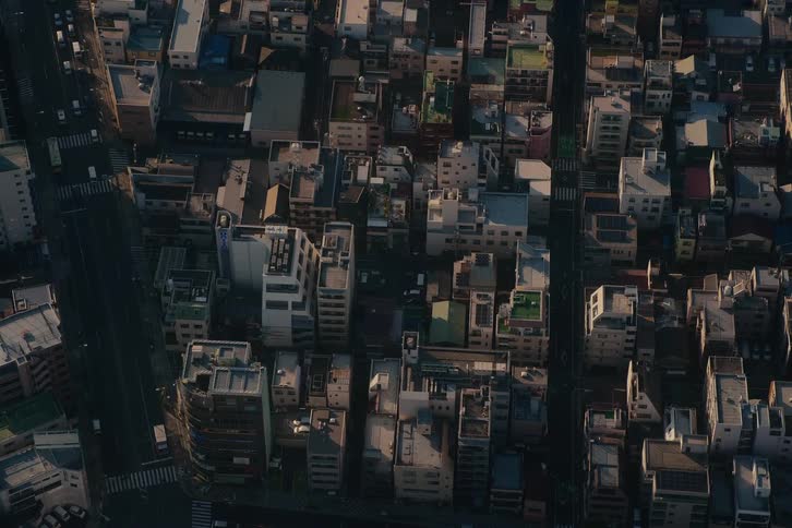 An aerial, top-down view captures traffic moving through the dense streets of a city during a beautiful sunrise