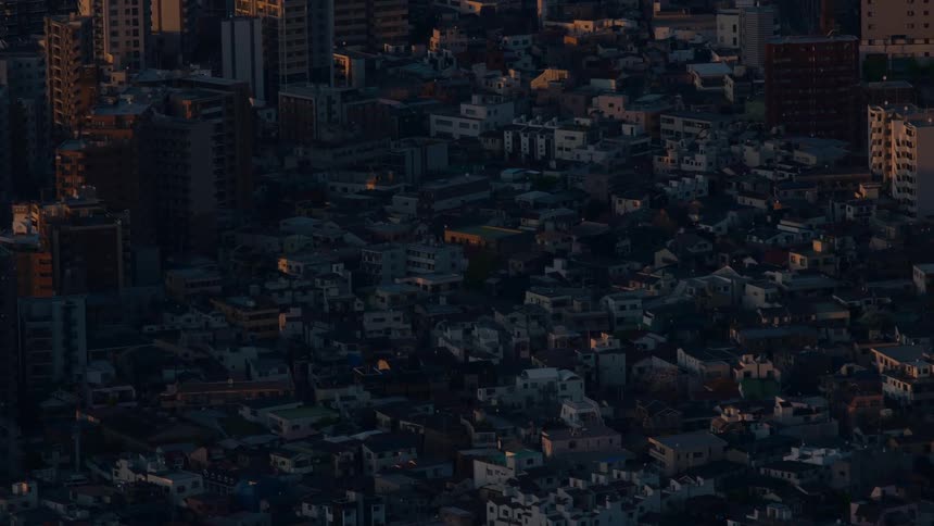A stunning time-lapse captures the last rays of golden sunlight fading over a dense urban cityscape as evening shadows take over