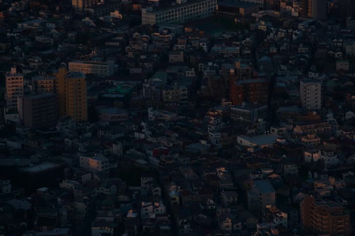 A static aerial shot of a dense residential cityscape as the last light of sunset fades to dusk