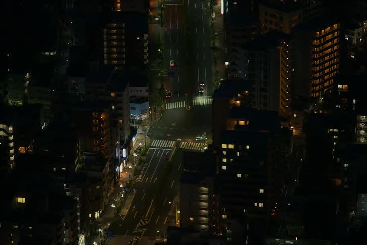 High-angle timelapse of cars driving through a quiet city intersection at night