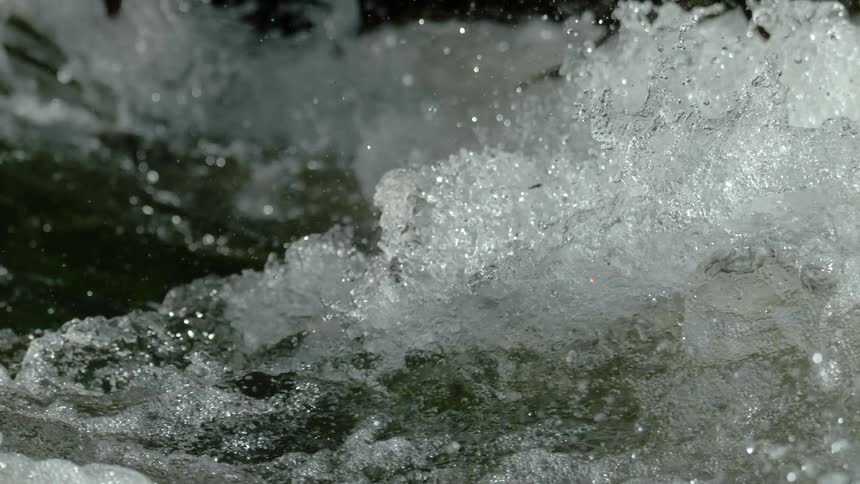 An extreme close-up of powerful whitewater churning and splashing in super slow motion