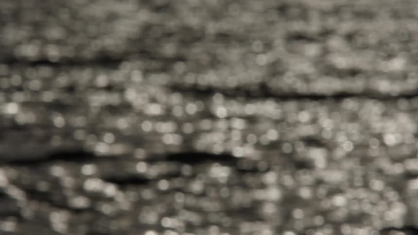 An abstract, out-of-focus view of water gently rippling as light sparkles across its surface, creating a beautiful bokeh effect