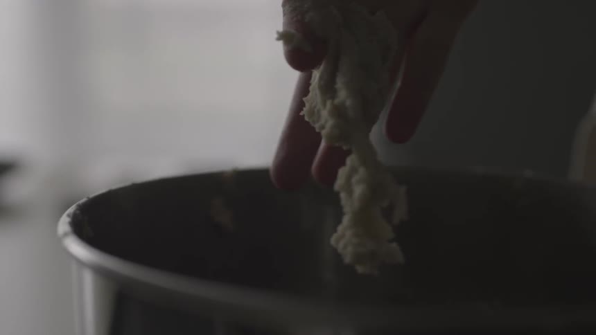 Woman pushes cookie batter of a wooden spoon with her finger