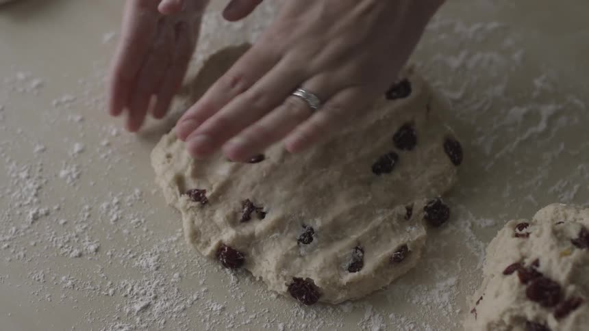 A person flattens out some cookie dough on a board