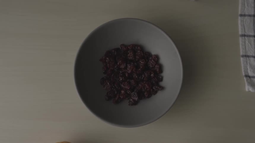 Person takes raisins in a bowl off a table