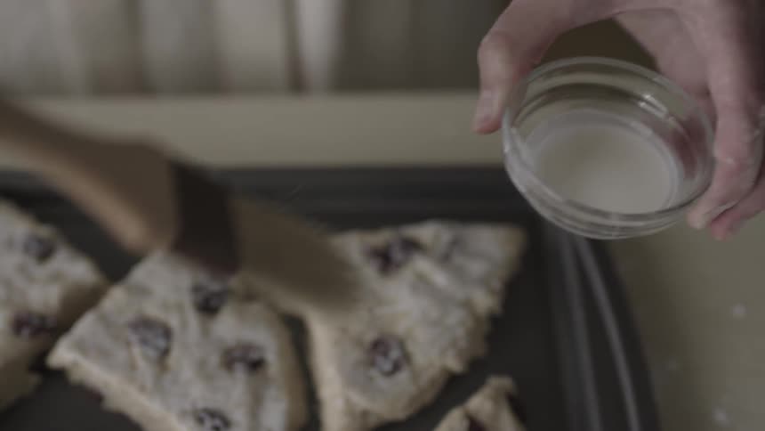 Person brushes melted butter onto raw cookie dough wedges