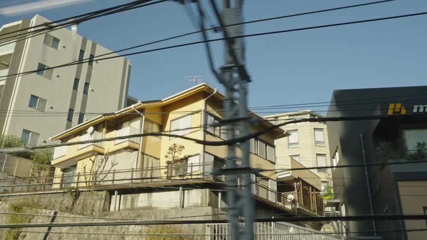 Looking out a train window at the passing homes and city buildings of a Japanese town