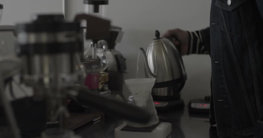 A man pours steaming water into a carafe and filter