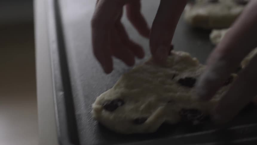 Person places raw cookie dough wedges onto a sheet pan