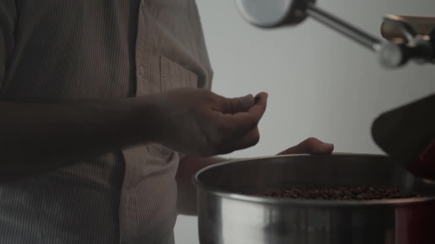 A man examines a coffee bean from a machine