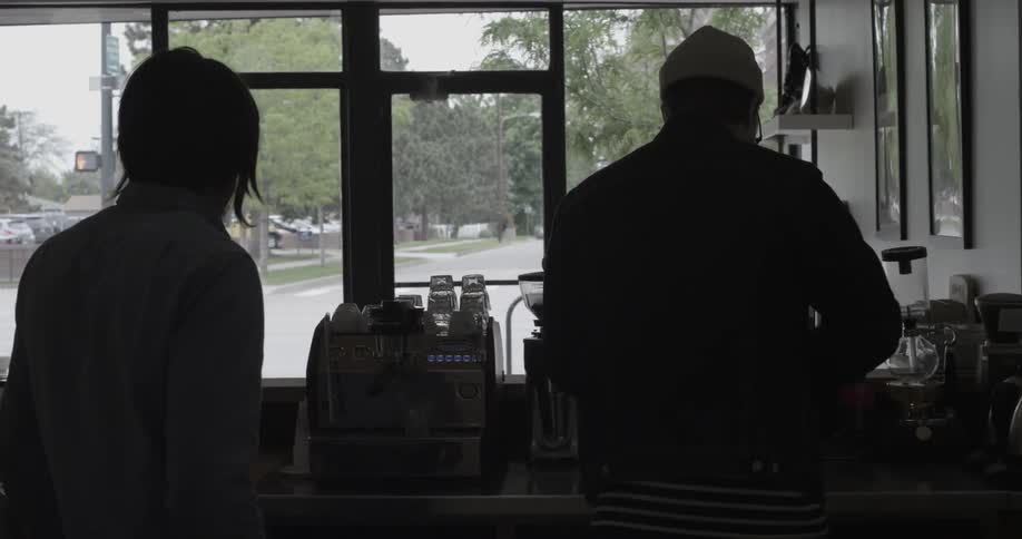 Two men are working behind a counter in a coffee shop