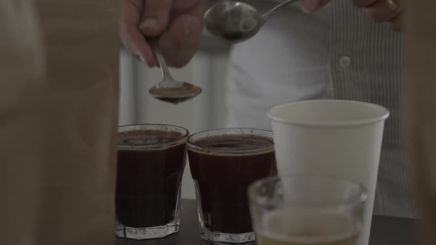 Person skimming liquid and pouring it into a white cup