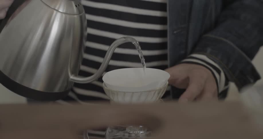 A person pours hot water into a coffee filter