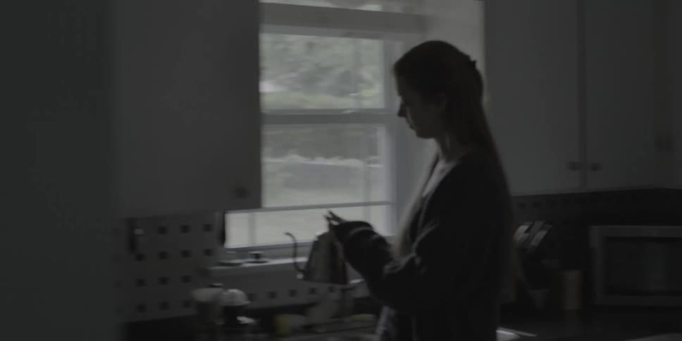 A woman walks to get a kettle to pour some coffee