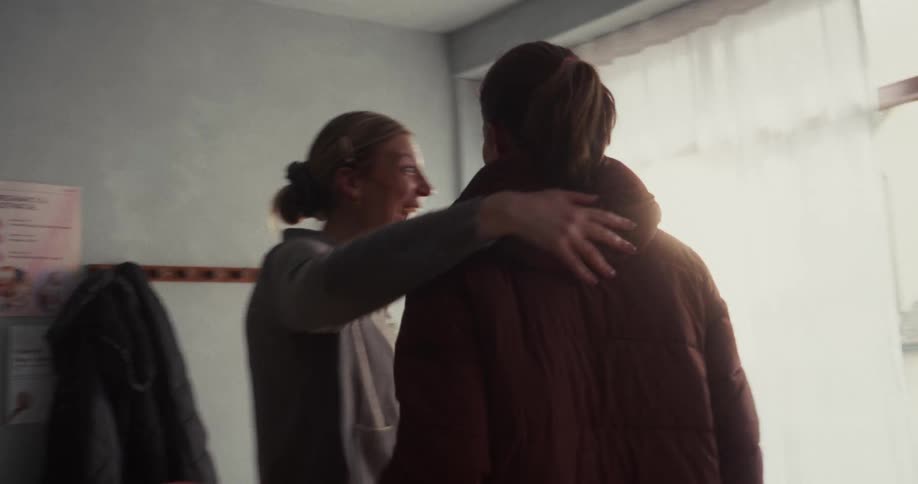 Smiling women greet each other with warm, happy hugs as they arrive for a community class in slow motion
