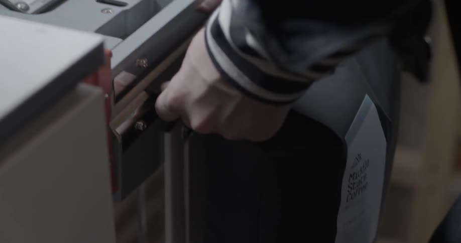 A man seals a bag of coffee with a machine