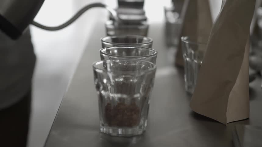 Liquid being poured from a kettle into several glasses